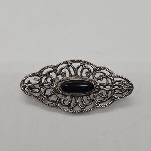 silver tone swirly brooch with black oval cabochon